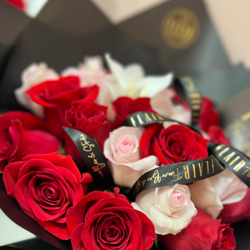 Bouquet of red and pink roses with a black ribbon wrapped in black paper.