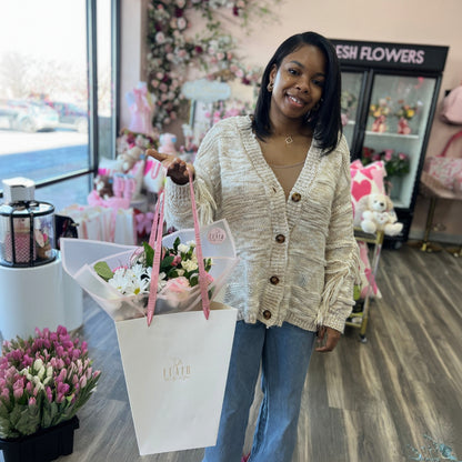 Woman holding a bouquet of flowers in a gift bag in Flair Flower Bar's flower shop.