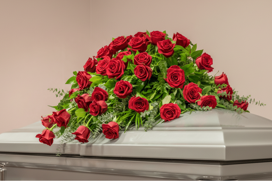 Silver casket with red roses on a light pink background for funeral service in Cincinnati or Northern Kentucky