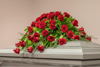 Silver casket with red roses on a light pink background for funeral service in Cincinnati or Northern Kentucky