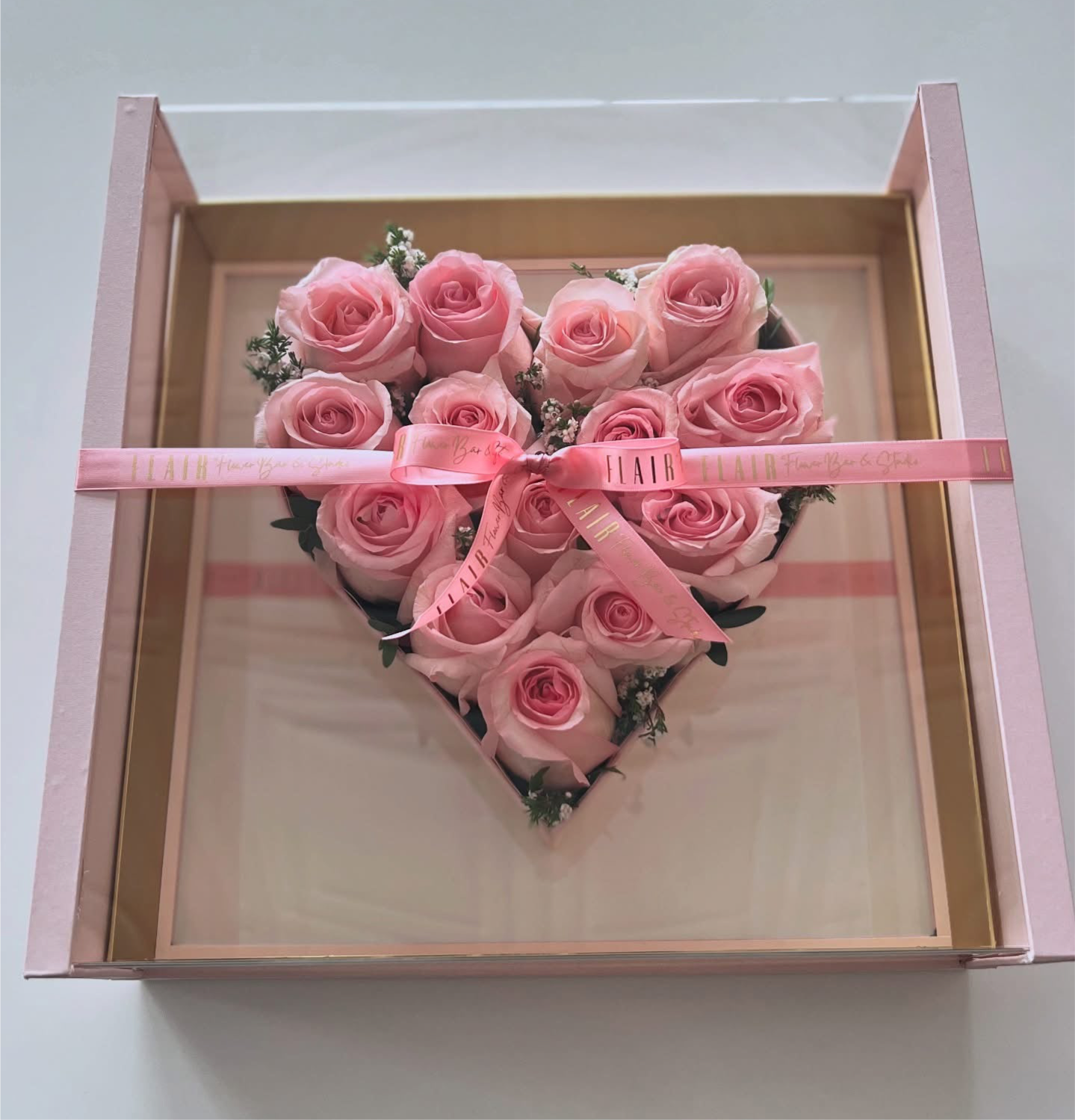 Heart-shaped arrangement of pink roses in a clear box with a pink ribbon from Flair Flower Bar in Florence, Ky