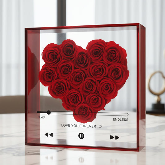 Heart-shaped arrangement of preserved red roses in a decorative clear box on a table with romantic home decor. Delivery in Northern Kentucky and Cincinnati by Flair Flower Bar in Florence, Kentucky