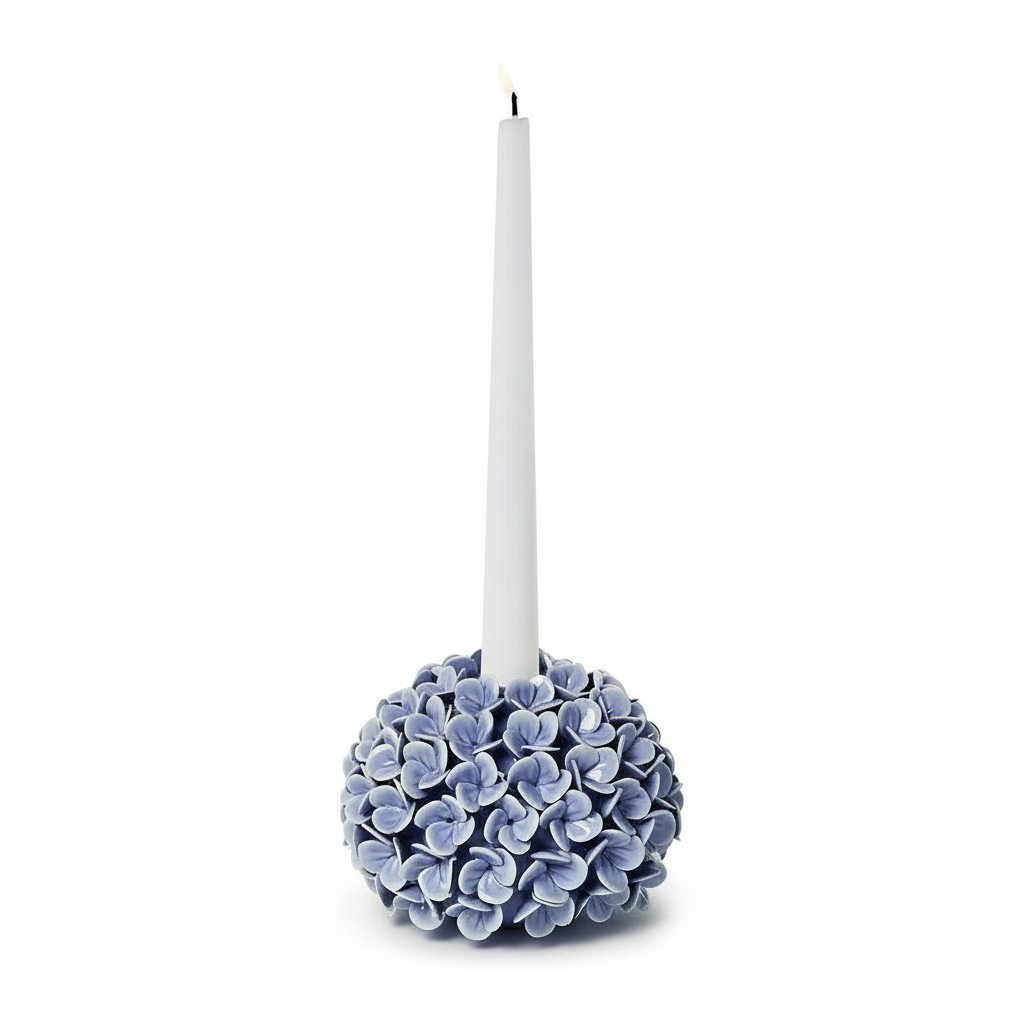 Decorative candle holder with blue hydrangea flowers and a white candle on a white background