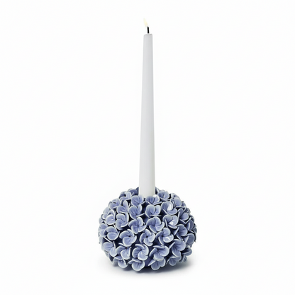 Decorative candle holder with blue hydrangea flowers and a white candle on a white background