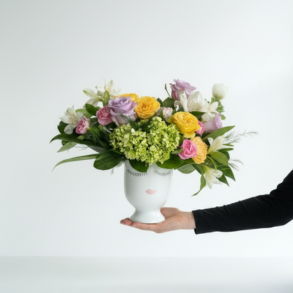 Hand holding a white vase with a colorful bouquet of flowers against a white background from Flair Flower Bar in Florence, Ky