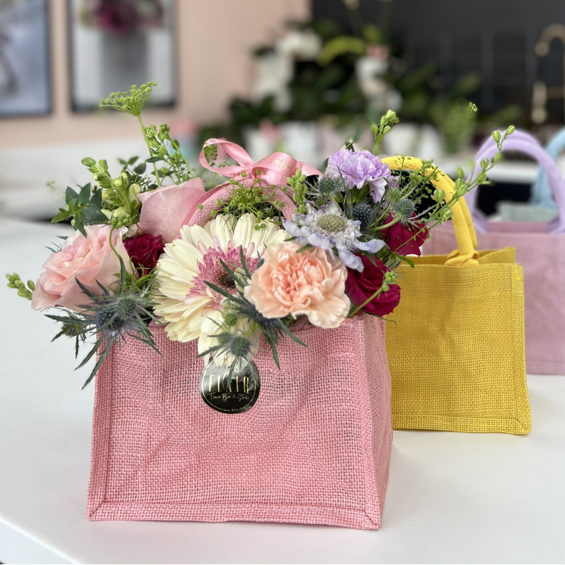 Floral arrangements in colorful bags on a table with 'Flair' branding in the background.