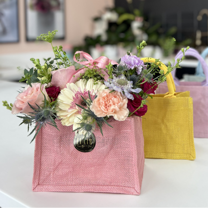 Floral arrangements in colorful bags on a table with 'Flair' branding in the background.