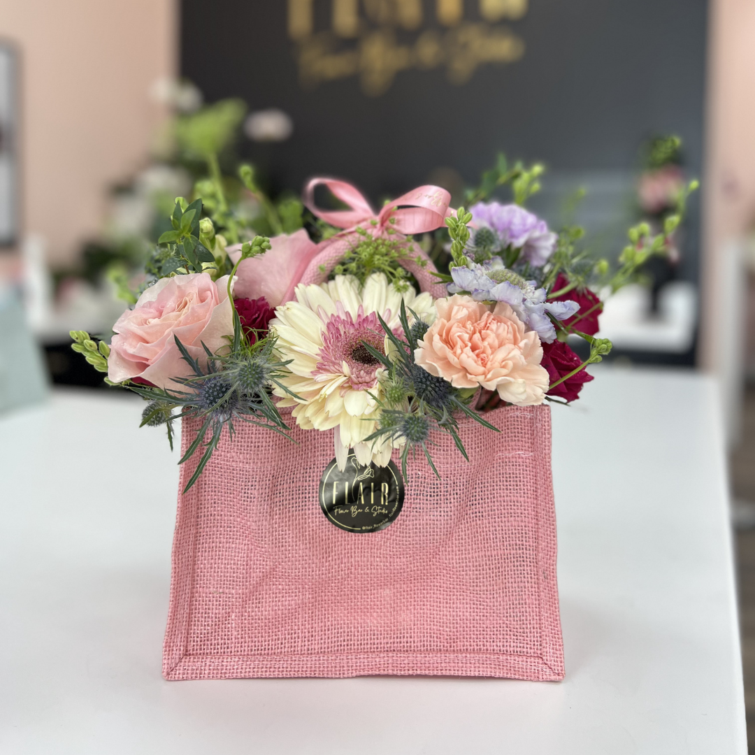 Pink bag with flowers in front of a blurred background with 'Flair' branding in Florence, Kentucky Store location