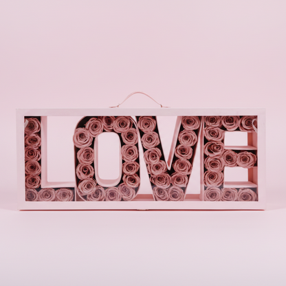 Decorative wall art with 'LOVE' spelled out using pink roses on a pink background.