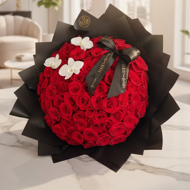 Round-shaped bouquet of red roses with white flowers and a black ribbon on a black flower wrap.