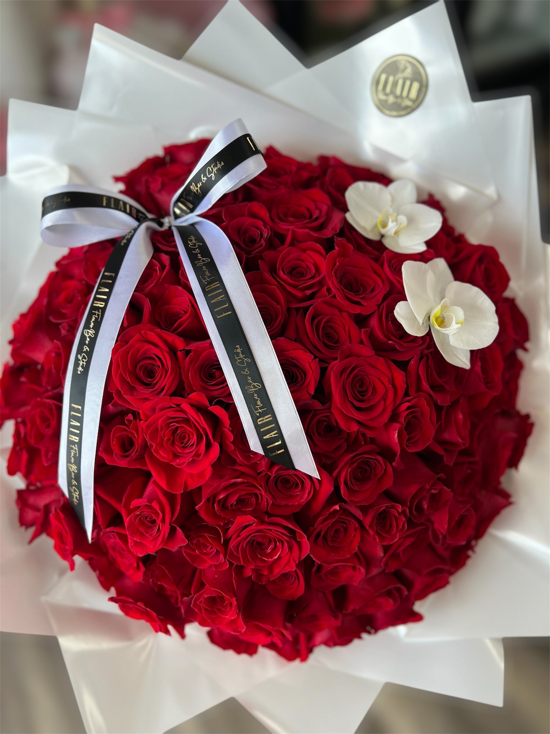 Bouquet of red roses with a white ribbon and two white orchids on a white background