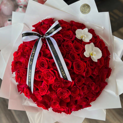 Bouquet of red roses with a white ribbon and two white orchids on a white background.