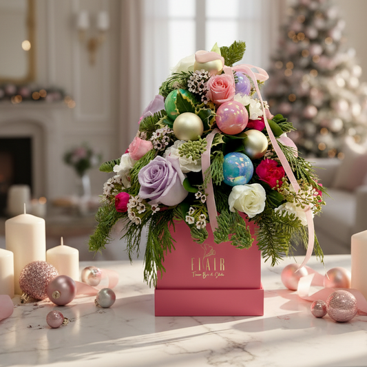 Decorative floral arrangement in a pink box with Christmas ornaments on a table.
