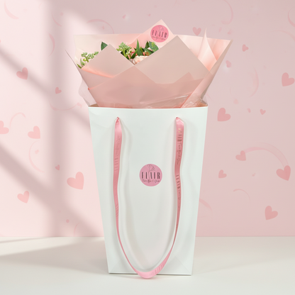 Bouquet of valentine flowers in a white and pink gift bag on white floor with heart backdrop for delivery throughout Northern Kentucky and Cincinnati