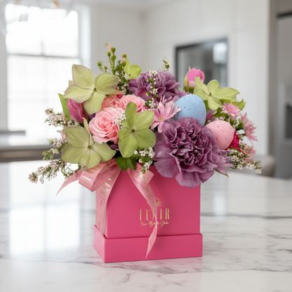Easter Floral arrangement in a pink box with 'FLAIR" branding on a marble surface.