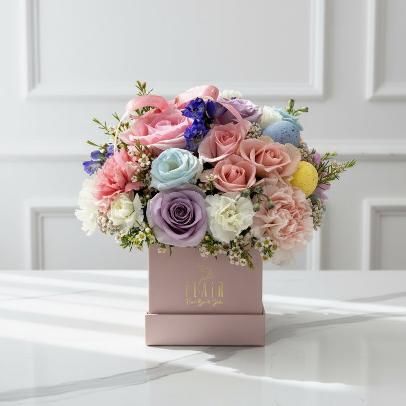 Colorful bouquet of flowers in a decorative box with a brand name on a white background