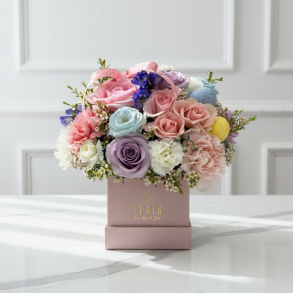 Colorful bouquet of flowers in a decorative box with a brand name on a white background