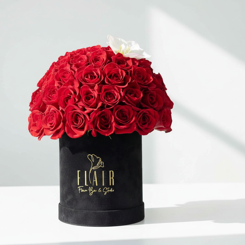 Black velvet box with red roses and a white roses on a light gray background