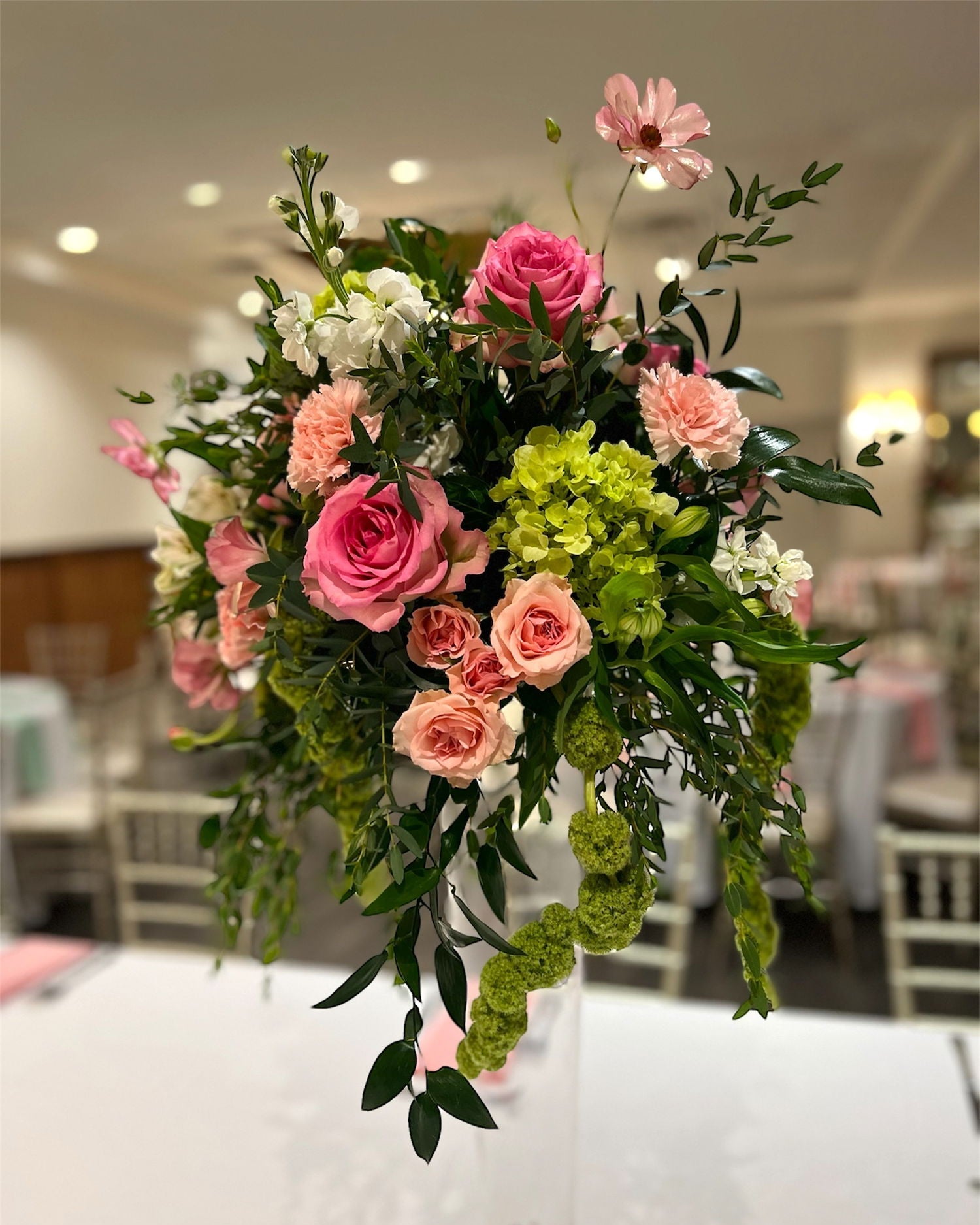 The Madison Covington Kentucky Bouquet of pink, green, and white flowers in a vase on a table.