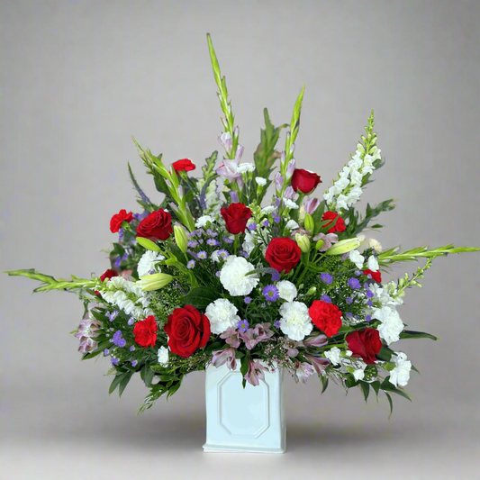 Floral Sympathy arrangement with red, white, and green flowers in a white vase on a light gray background