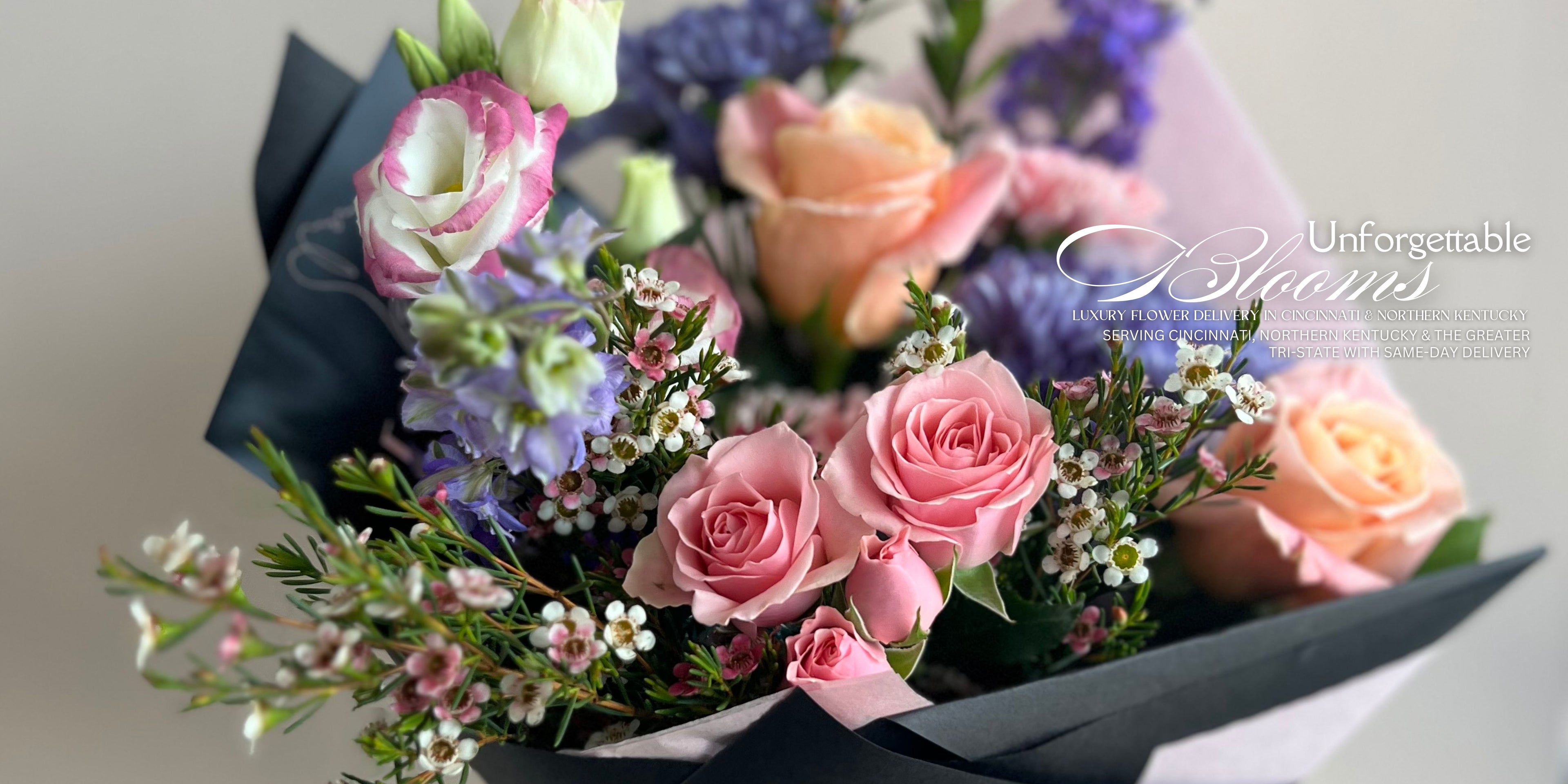 Bouquet of pink and white roses with greenery, branded 'Unforgettable Blooms'.