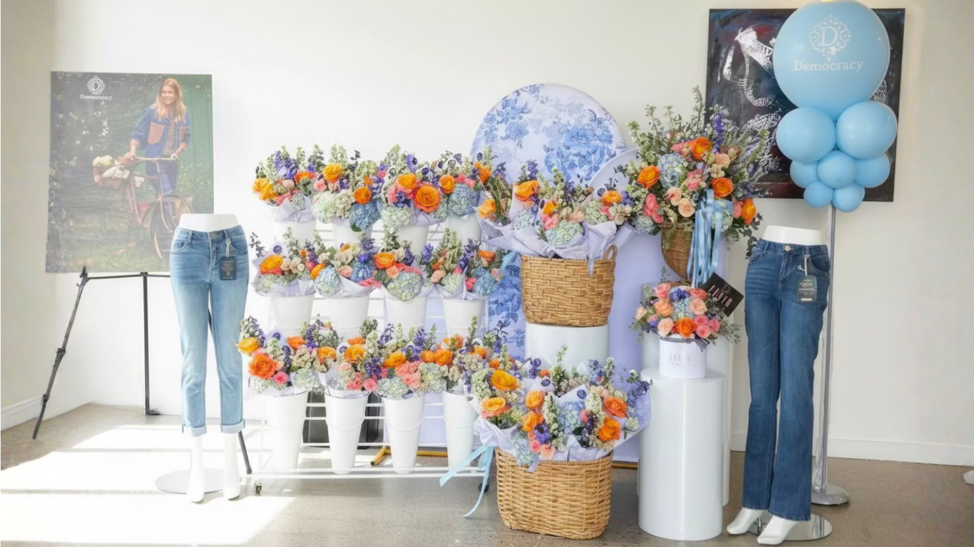 Brand ACTIVATION Display of Democracy jeans and floral arrangements in a store setting with balloons and posters.