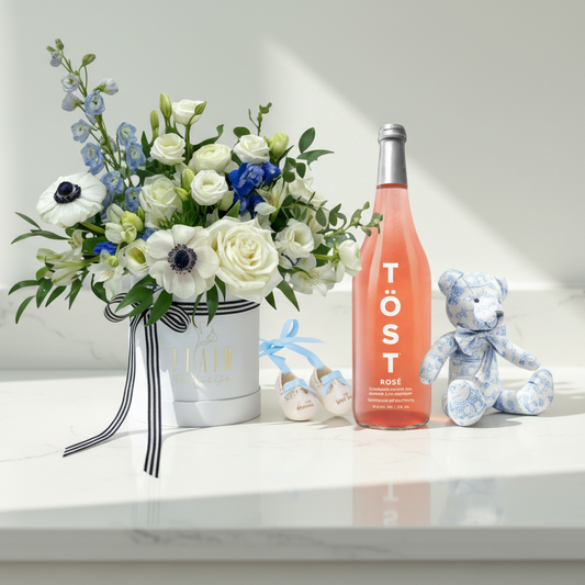 Bottle of Töst Rosé, bouquet of flowers, and teddy bear on a white background