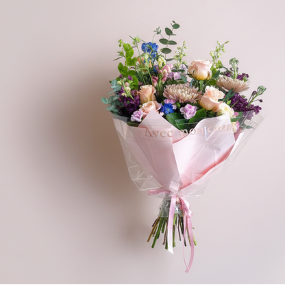 Bouquet of flowers wrapped in pink paper with on a light background by Flair Flower Bar in Florence, Kentucky