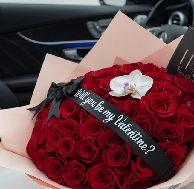 Bouquet of red roses with a white orchid and 'Will you be my Valentine?' ribbon inside a car.