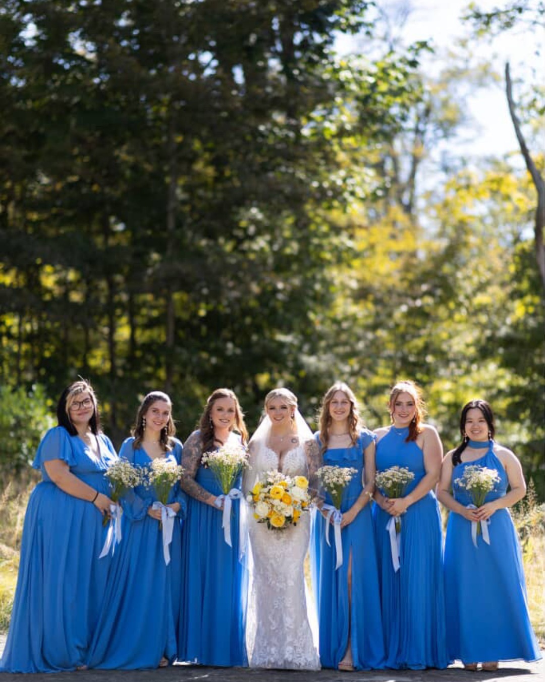 Wedding arch Cincinnati Nature Center_Groesbeck Estate Bride with bridesmaids in blue dresses outdoors with trees in the background