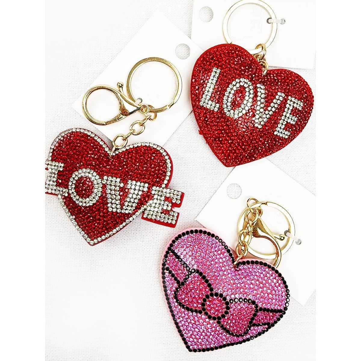 Heart-shaped keychains with 'LOVE' and bow designs on a white background