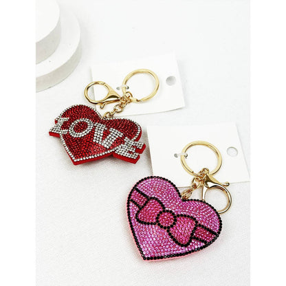 Two heart-shaped keychains, one red with 'LOVE' and the other pink with a bow design, on a white background.