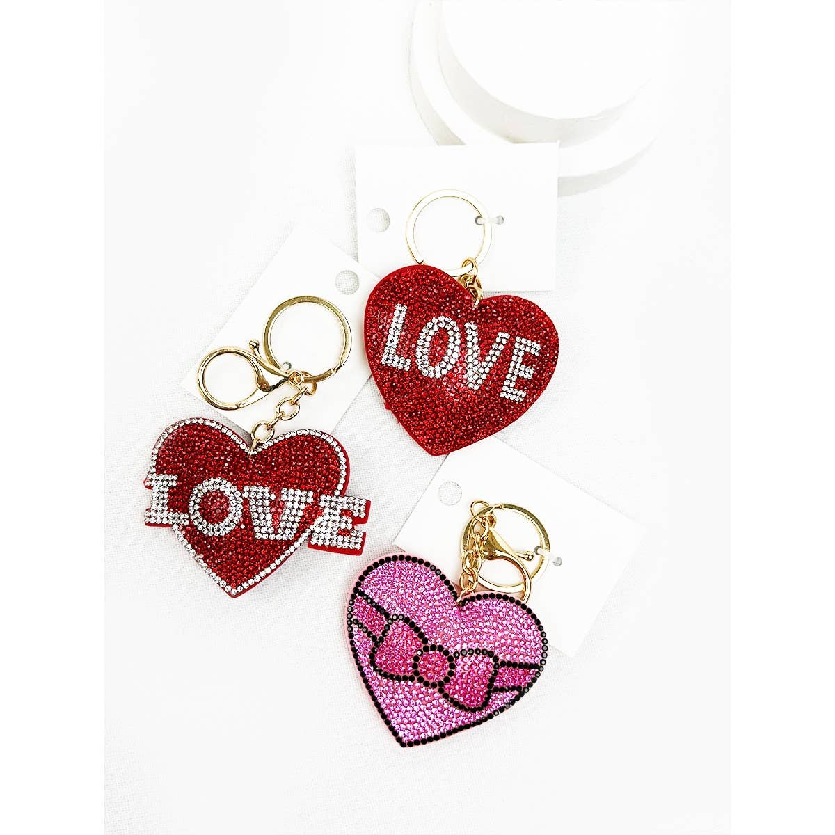 Heart-shaped keychains with 'LOVE' and bow designs on a white background