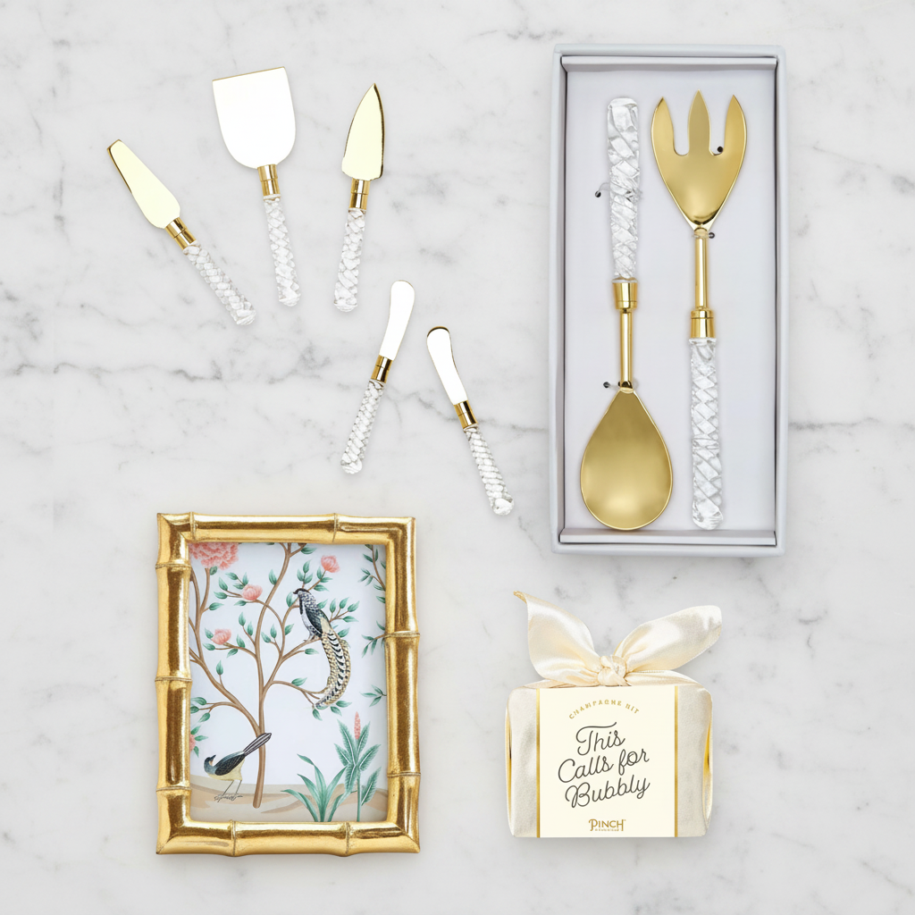 Gold wedding cutlery set with decorative box and gold frame on a marble surface