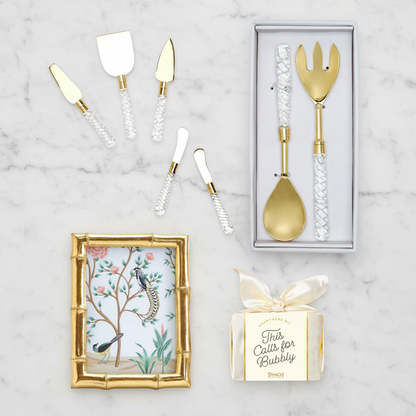 Gold wedding cutlery set with decorative box and gold frame on a marble surface