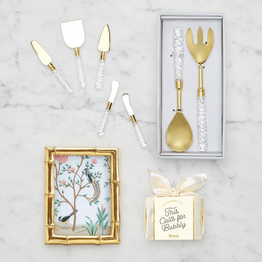 Gold wedding cutlery set with decorative box and gold frame on a marble surface