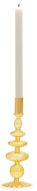 Gold candle holder with a white candle on a plain background